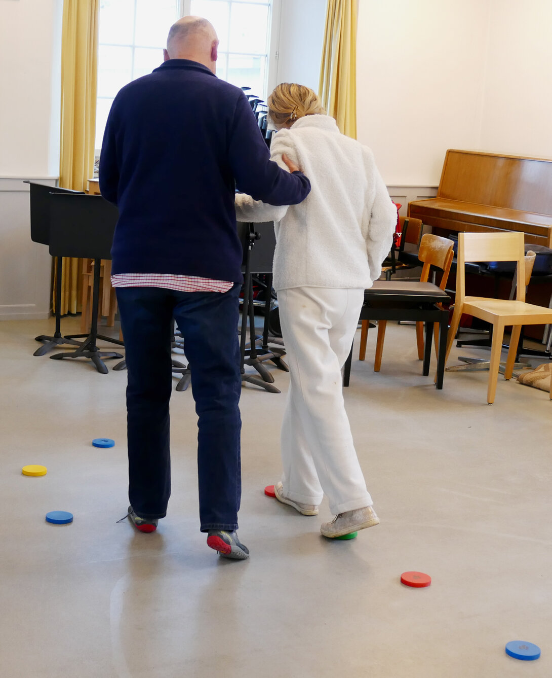 Seniorin hält sich an einem Stuhl fest und übt das Gleichgewicht.